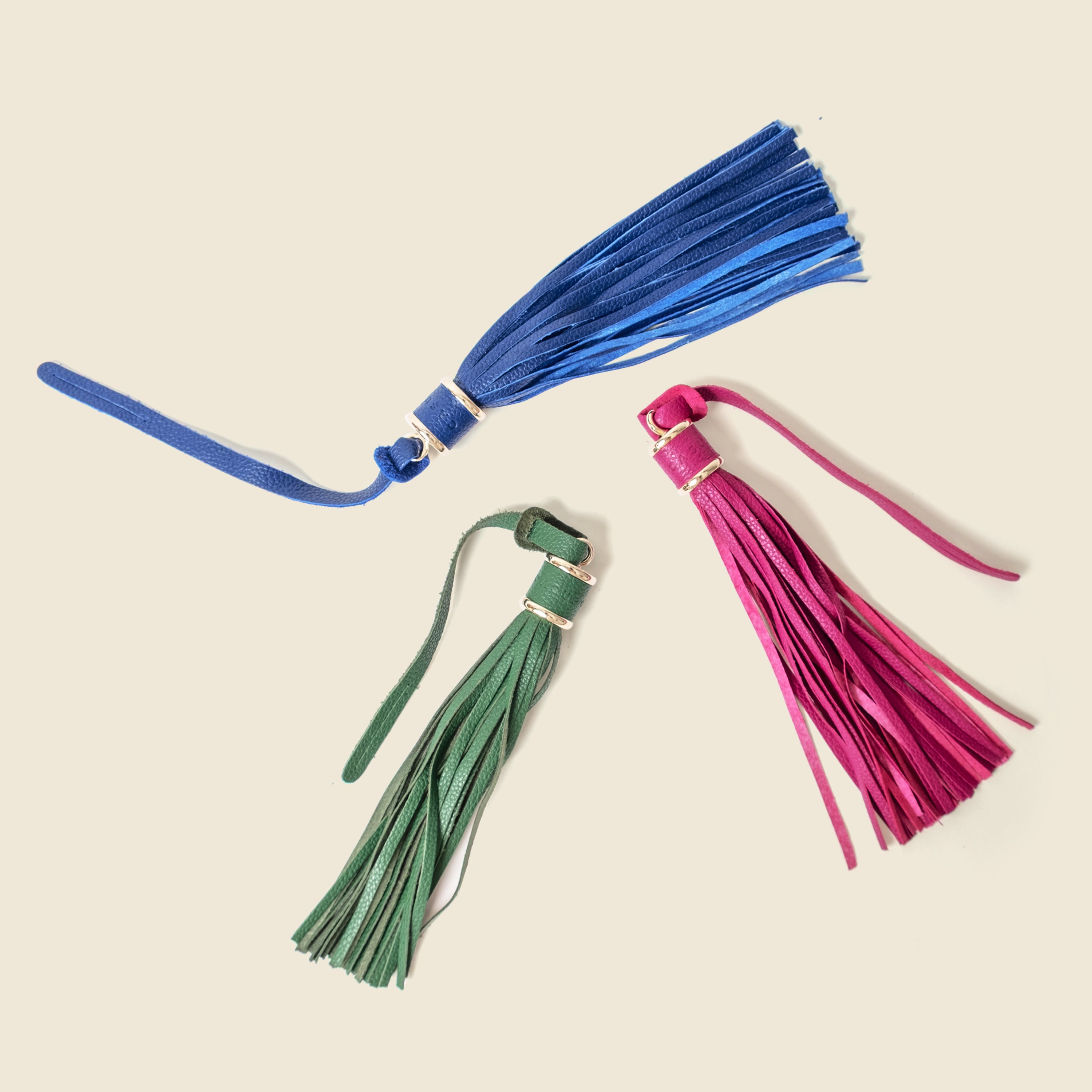 Three colorful tassels on a beige background