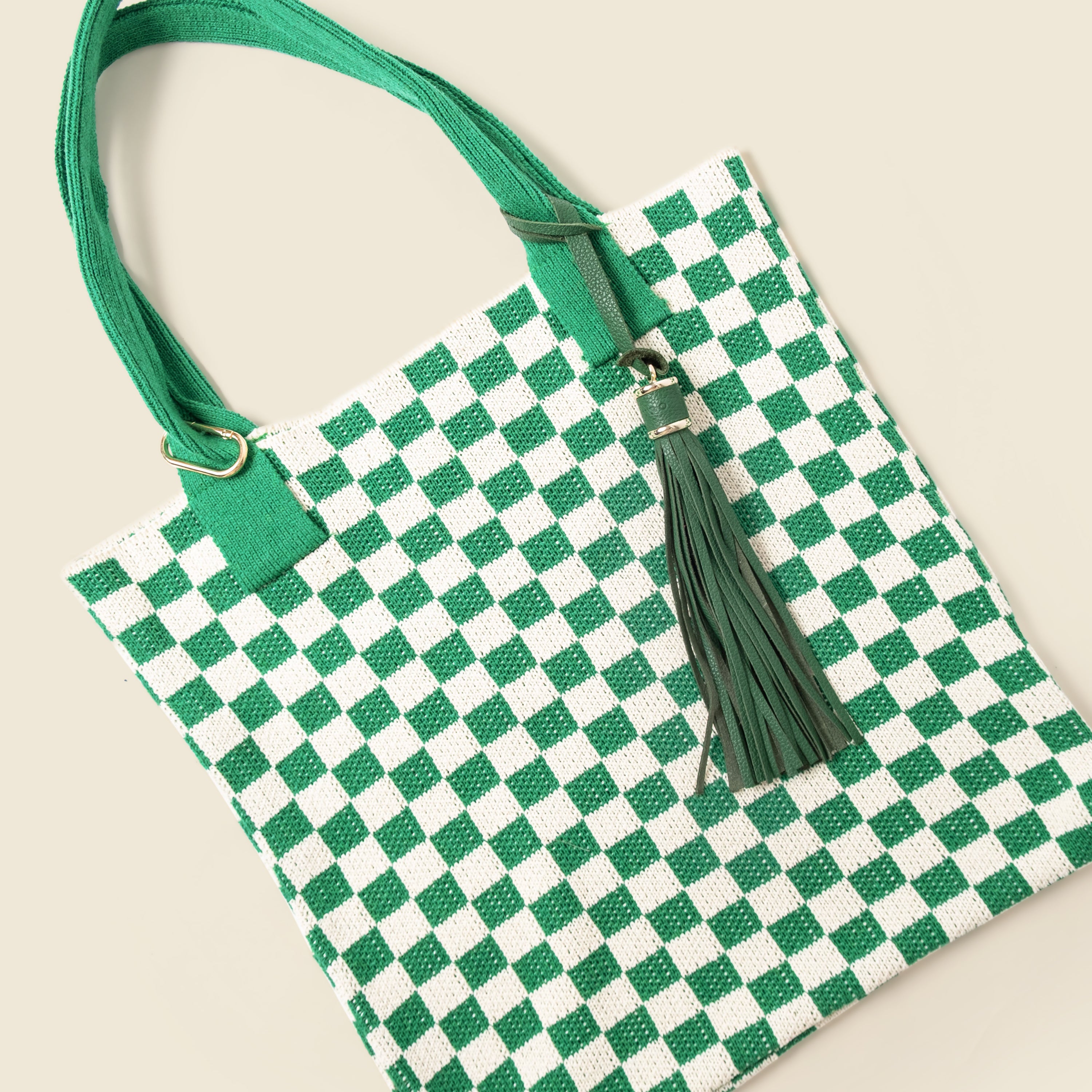 Green and white checkered bag with a tassel on a beige background