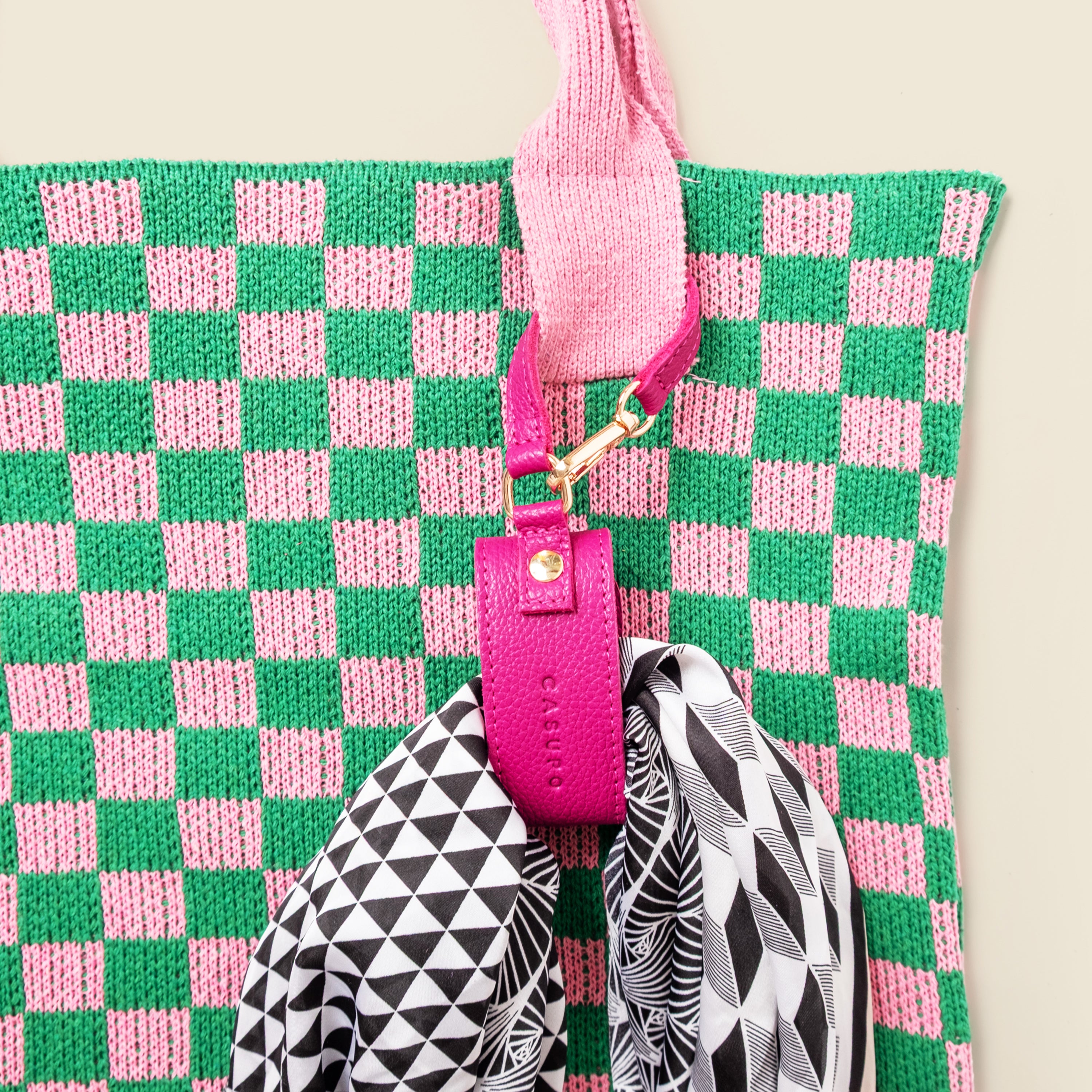 Green and pink checkered bag with a pink strap and geometric pouches.