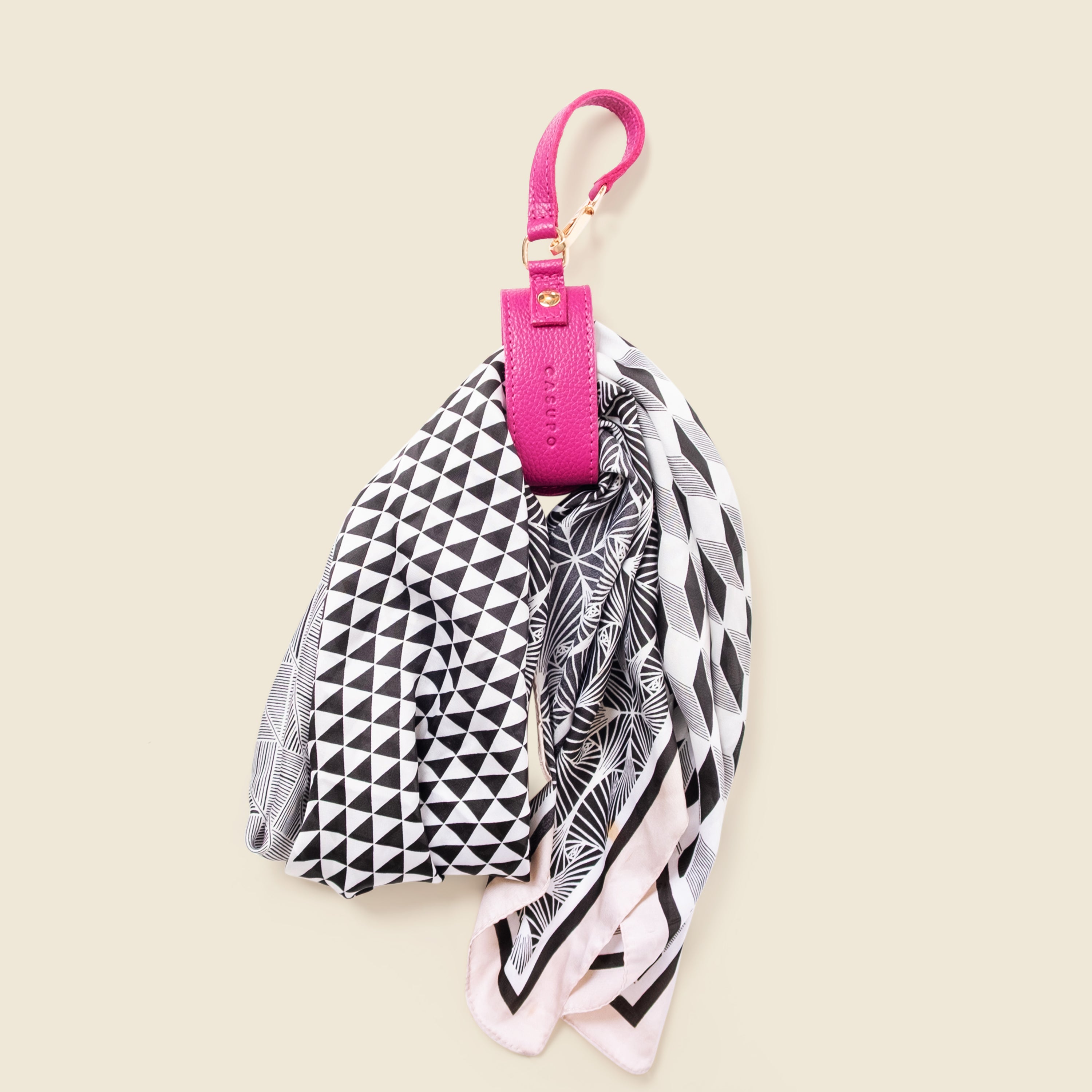Black and white geometric patterned scarf with a pink holder on a beige background
