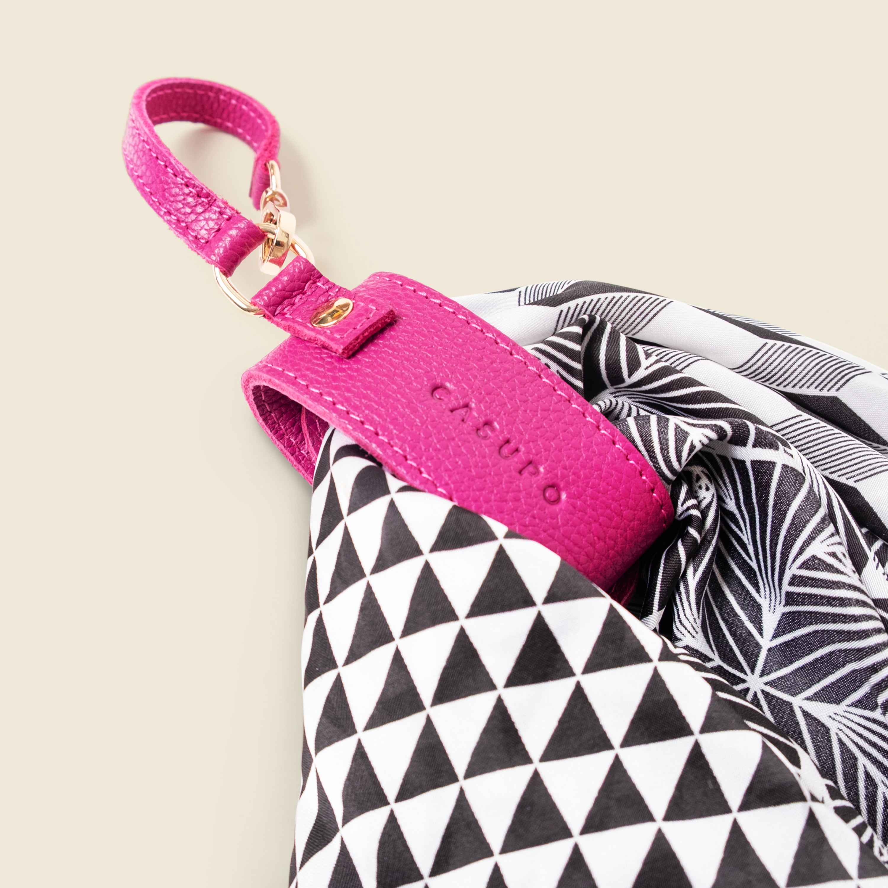 Pink keychain with CASUPO logo on a black and white patterned fabric background