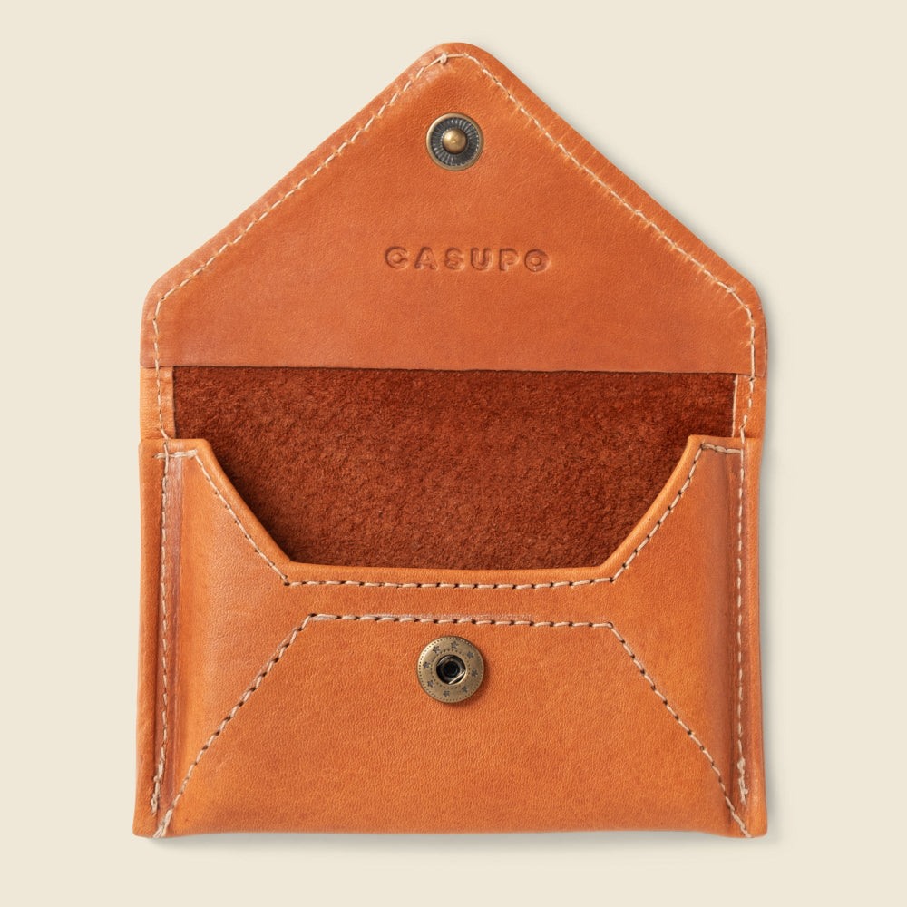 Brown leather wallet with visible brand name on a beige background