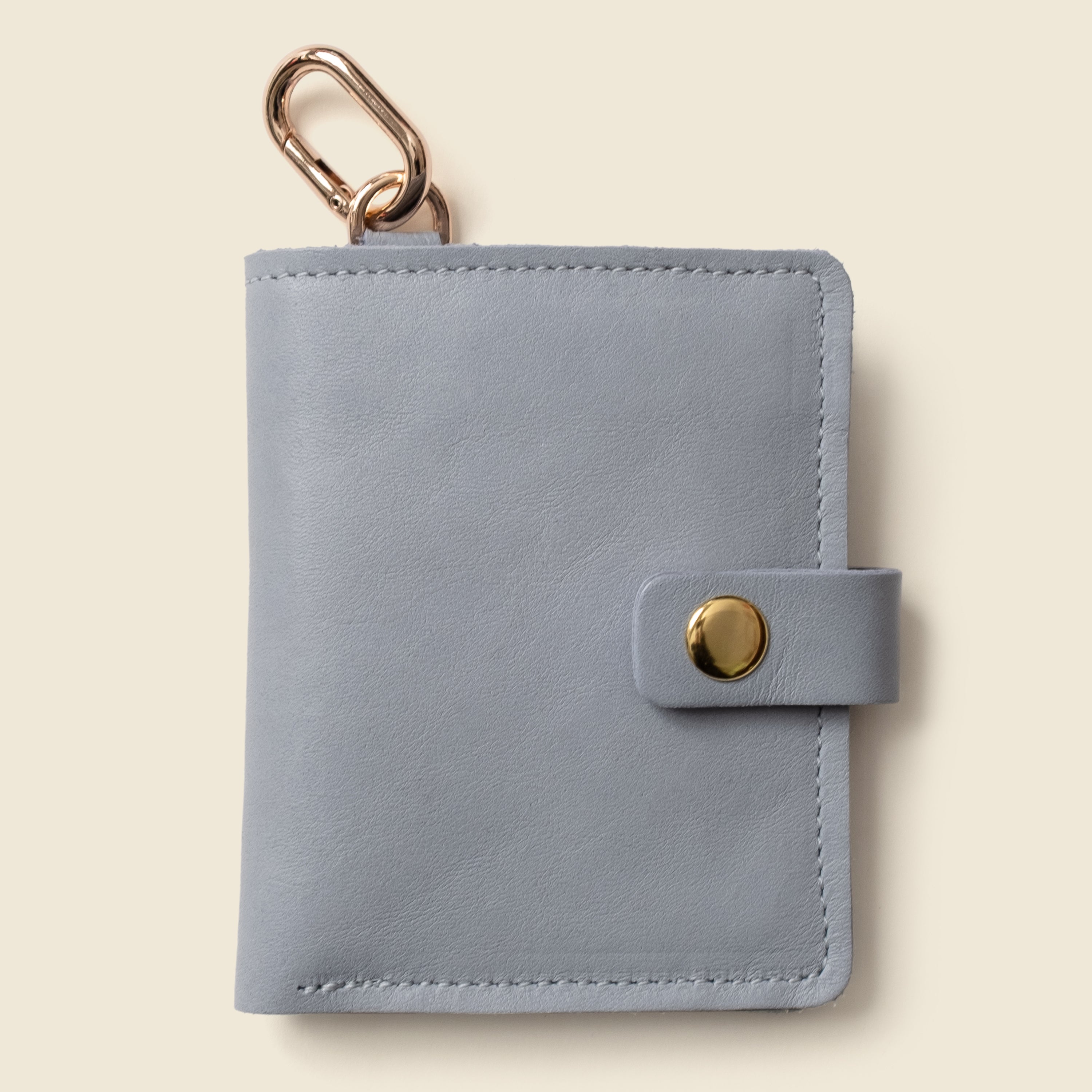 Ice blue leather snap wallet with key ring on beige background 