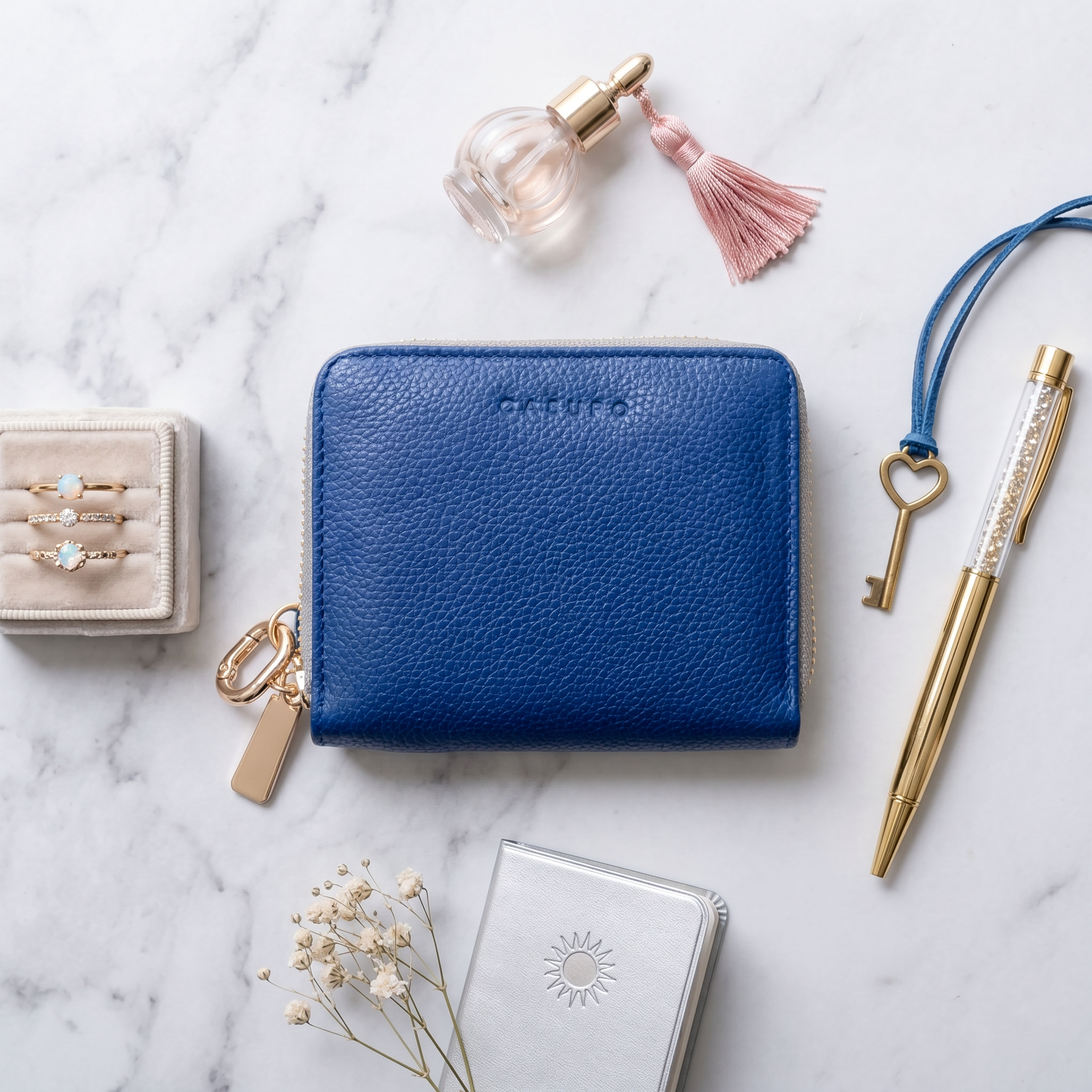 Blue wallet on a marble surface with jewelry, pen, and key
