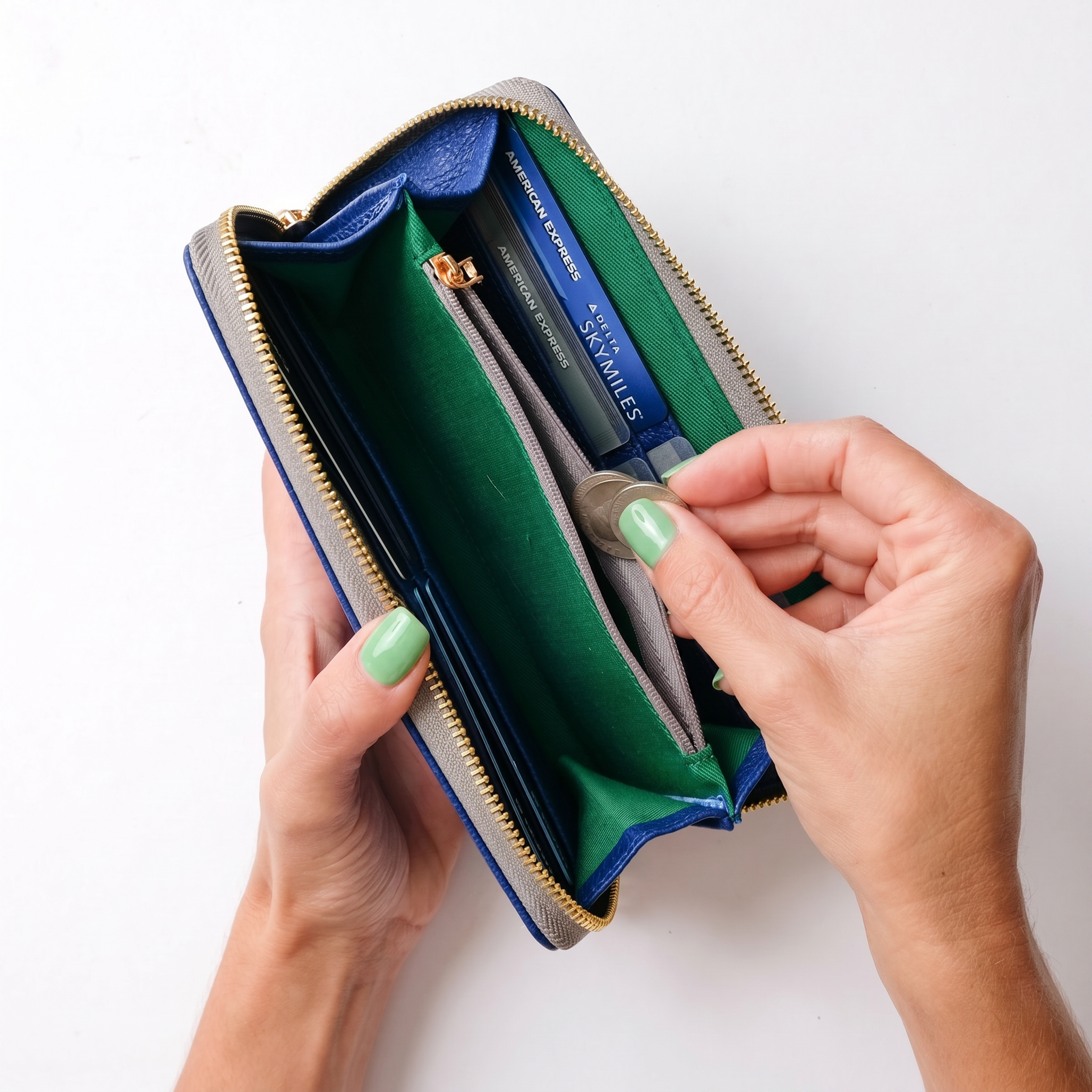 Person holding a green and blue wallet with a white background